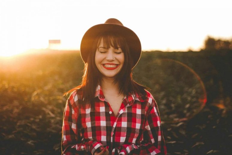 a woman with a hat smiling with her teeth