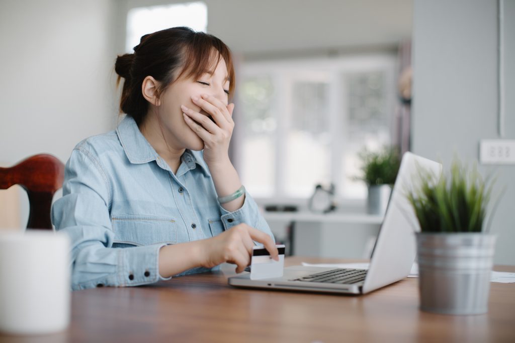 a woman yawning while using a laptop