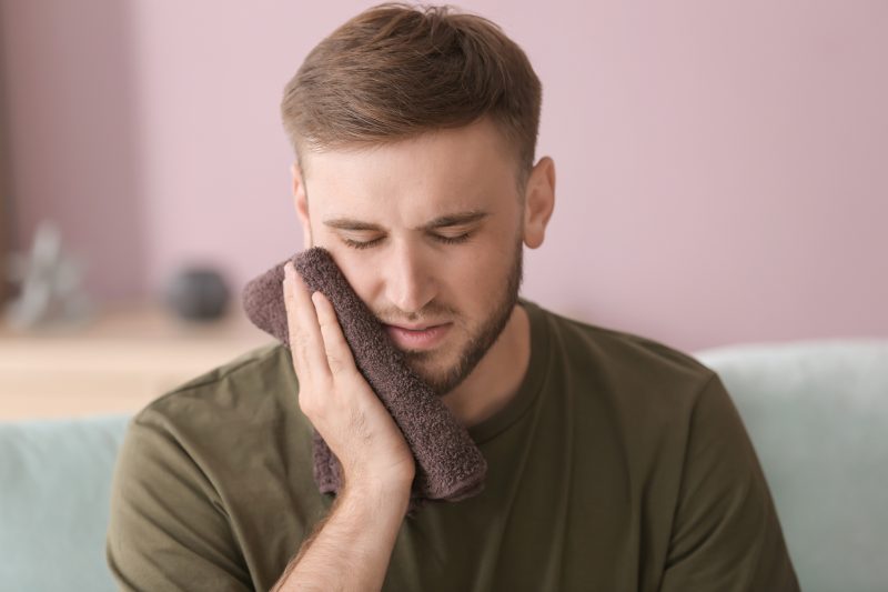 Young man suffering from toothache at home